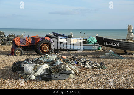 Offene Fischerboote wurden auf dem Kiesel des Bognor Beach, West Sussex, Großbritannien, hochgezogen. Zeigt Netze und Hummertöpfe im Vordergrund Stockfoto