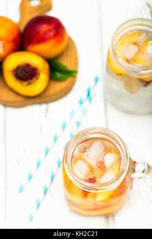 Hausgemachte Eistee Limonade mit reife Pfirsiche. Frischer pfirsich Eistee in einem Marmeladenglas. top View Stockfoto