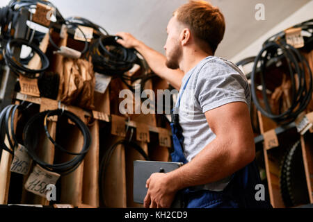 Low Angle Porträt der jungen Mechaniker Prüfung bestand dabei bestand in der industriellen Tools Store Stockfoto