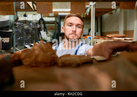 Porträt der jungen Mechaniker auf der Suche nach Teile im Regal im Lagerraum während der Bestandsaufnahme Stockfoto