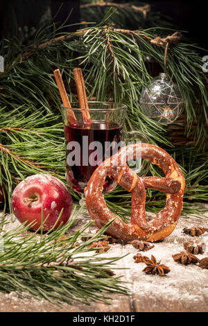 Ein Glas Glühwein, einen Apfel und eine Brezel auf einem Tisch in der Nähe der Weihnachtsbaum in einem Haus Stockfoto