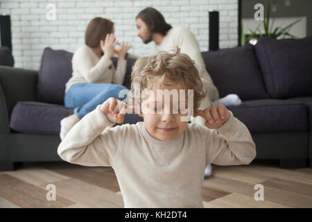 Kleiner Junge die Finger in die Ohren nicht zu hören Eltern im Hintergrund kämpfen, traurig müde Sohn leiden von Mama und Papa streiten, elterliche Konflikte Hur Stockfoto