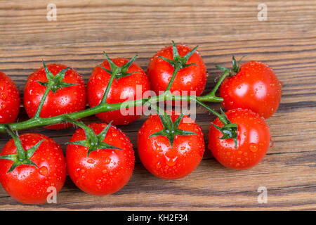 Bündel von frischen Tomaten mit Wassertropfen. saftige Bio Gemüse voller Vitamine und Antioxidantien auf Holz- Hintergrund. Stockfoto