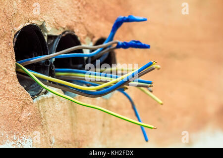 Ausbauarbeiten an der renovierte Apartment. elektrische Verkabelung Installation. Elektrische freiliegende Drähte ragt aus der Fassung auf der alten Mauer Stockfoto