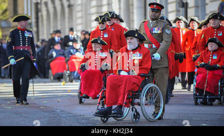 London, Großbritannien. 12. November 2017. Lance Sergeant Johnson Gideon Beharry, VC, CNG, schiebt eine Chelsea Rentner in einem Rollstuhl auf dem Weg zu Horse Guards Parade. Große Menschenmassen versammeln sich um den Parliament Square und Whitehall auf das Gedenken Sonntag, wo die Mitglieder der königlichen Familie, dignatories und Veteranen gab Tribute zu den Krieg tot am Ehrenmal. Credit: Stephen Chung/Alamy leben Nachrichten Stockfoto