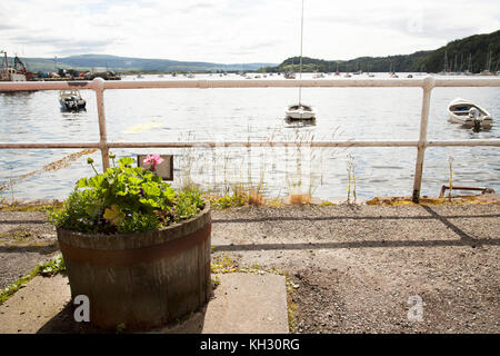 Pflanzmaschine von Holzfass mit Blumen der roten Geranien an der Küste mit Blick auf den Port die Stockfoto