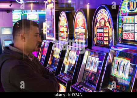 Ein Mann spielt die Spielautomaten in eine Spielhalle in Chinatown im Londoner West End, Großbritannien Stockfoto