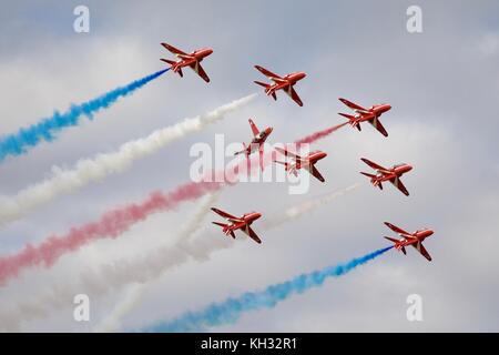 Die Royal Air Force Red Arrows Kunstflugstaffel mit roten, weißen und blauen Rauch Wanderwege Stockfoto