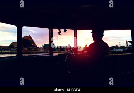 Sonnenuntergang Bangkok Riverside Blick von hinten beleuchtete Silhouette - das Boot der Fenster Stockfoto
