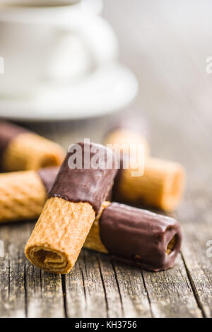 Süße Nachspeise. Kekse Brötchen mit Schokoladenglasur auf alten Holztisch. Stockfoto