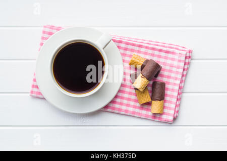 Süße Nachspeise. Kekse Brötchen mit Schokoladenglasur und Kaffeetasse. Stockfoto