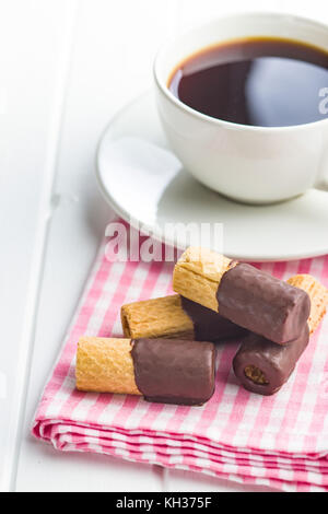 Süße Nachspeise. Kekse Brötchen mit Schokoladenglasur und Kaffeetasse. Stockfoto