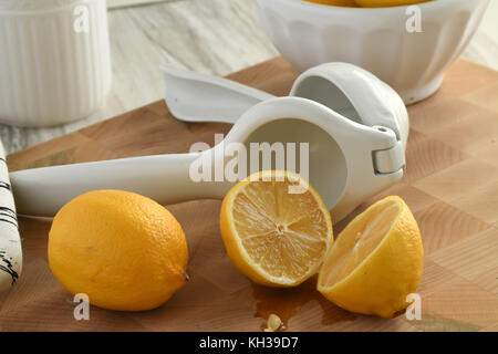 Frische organische Zitronen - in Weiß und Gelb mit Citrus hand- Saftpresse, leicht und hell auf einem hölzernen Schneidebrett Stockfoto