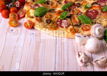 Pizza mit Salami Gemüse und Gewürze auf einem weißen Holz- Hintergrund mit Kopie Raum Stockfoto