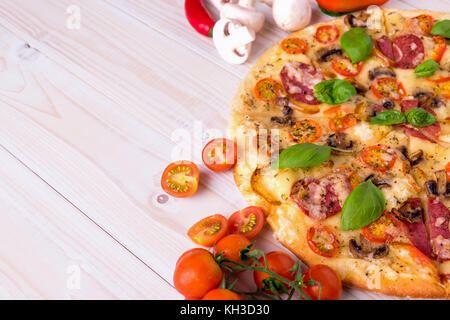 Pizza mit Salami Gemüse und Gewürze auf einem weißen Holz- Hintergrund mit kopieren. Stockfoto