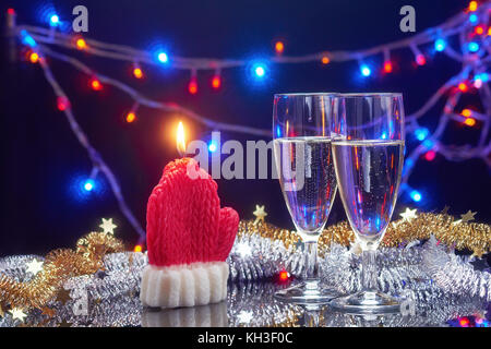 Neues Jahr Karte mit Weihnachten dekorative Kerze santa claus Handschuh und 2 Sektgläser über Girlande bokeh hellen Hintergrund Stockfoto