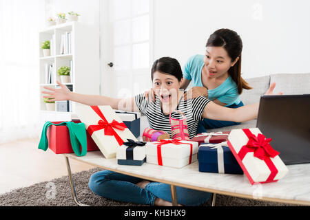 Gerne hübsche Freundinnen empfing viele Sommer verkauf Geschenkbox Gefühl überrascht und sitzen im Wohnzimmer zusammen bereit, eröffnet. Stockfoto