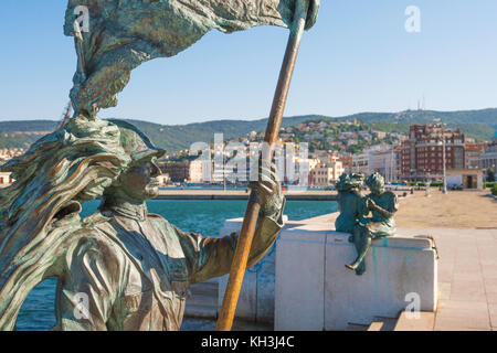 Hafen von Triest, Blick im Sommer auf eine Bronzestatue, die einen fahnenschwingenden Soldaten an der Strandpromenade im italienischen Hafen von Triest darstellt. Stockfoto