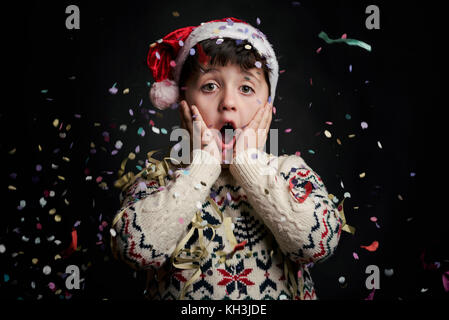 Überrascht Kind in Silvester auf schwarzem Hintergrund Stockfoto