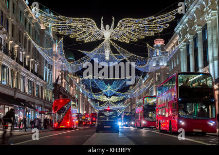 Rote Doppeldeckerbusse fahren Sie unter funkelnden Weihnachtsbeleuchtung entlang der schönsten Einkaufsstraßen der Regent Street. Stockfoto