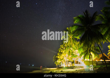 Nachthimmel Sterne über Strand mit Haus und Palmen. Stockfoto