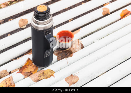 Touristische Thermoskanne mit Schale steht auf weiße Bank im Herbst Park Stockfoto