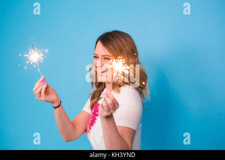 Portrait eines glücklichen Frau mit bengalischen Lichter über blauen Hintergrund. Weihnachten, Feste und Feiertage Konzept Stockfoto