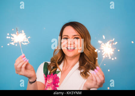 Portrait eines glücklichen Frau mit bengalischen Lichter über blauen Hintergrund. Weihnachten, Feste und Feiertage Konzept Stockfoto