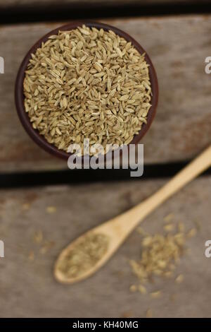 Hölzerne Schüssel mit Fenchel Samen und einem Löffel aus Holz mit Fenchel Samen über ein Holzdeck gefüllt Stockfoto