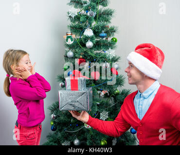 Santa Claus gibt ein Geschenk unter dem Weihnachtsbaum Mädchen Stockfoto