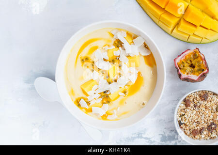 Mango smoothie Schüssel mit Kokosnuss, Müsli und Passionsfrucht. Gesunde vegane Ernährung frühstück Konzept. Stockfoto