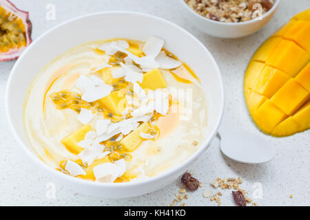 Mango smoothie Schüssel mit Kokosnuss, Müsli und Passionsfrucht. Gesunde vegane Ernährung frühstück Konzept. Stockfoto