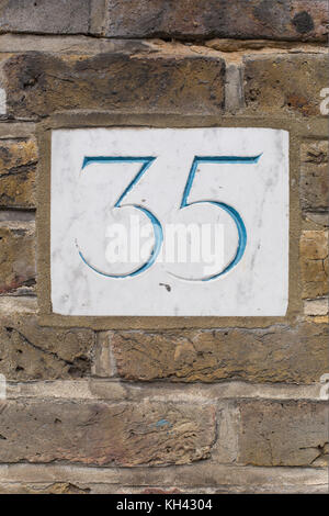 Geschnitzte Hausnummer die Platte an der Wand Stockfoto