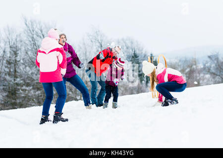 Familie mit Kindern in Schneeballschlacht im Winter Stockfoto