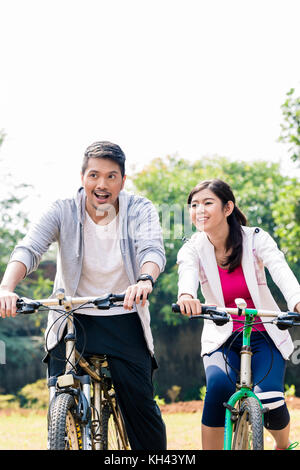 Jungen asiatischen Paar zusammen lachen, beim Reiten Fahrräder Stockfoto