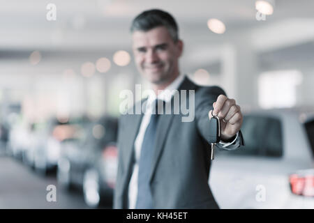 Lächelnd Autoverkäufer Übergabe ihres neuen Autoschlüssel, Händler- und Vertriebskonzept Stockfoto