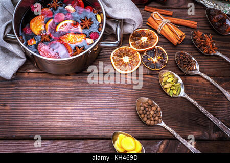 Glühwein in einem Topf und Löffel mit Zutaten für die Zubereitung von alkoholischen Getränken, leeren Raum in der Mitte Stockfoto