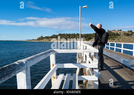 Victor Harbor, South Australia: 10. Juli 2017 - Kahle männliche Touristen auf dem Damm Anschluss der Gemeinde nach Granite Island, mit Blick in die Dist Stockfoto