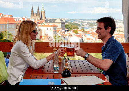 Junge touristische Paar Toasten mit Bier im Restaurant terrce Blick auf Prag, Tschechische Republik Stockfoto