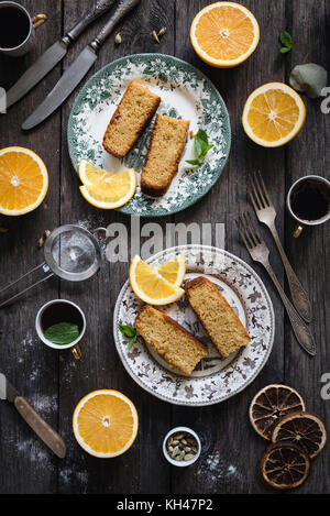 Orange Kuchen serviert auf vintage Platte auf rustikalen Holztisch Hintergrund. Essen still life. Ansicht von oben, vertikalen Zusammensetzung Stockfoto