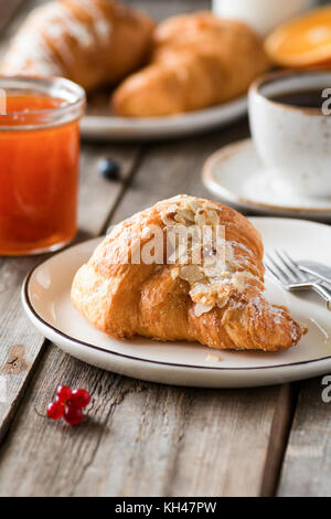 Croissant, Marmelade und Kaffee auf Holztisch. Kontinentales Frühstück, Mittagessen oder Brunch im Cafe. Detailansicht Stockfoto