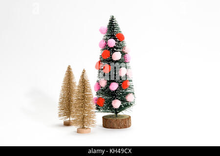 Isolierte Weihnachtsbaum mit Pompoms anstelle von christmad Kugel dekoriert mit zwei goldenen Bäumen, neben dem das minimale Still life Fotografie Stockfoto