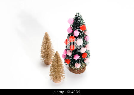 Isolierte Weihnachtsbaum mit Pompoms anstelle von christmad Kugel dekoriert mit zwei goldenen Bäumen, neben dem das minimale Still life Fotografie Stockfoto