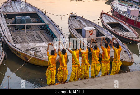 Jungen Hindu Priester bieten Wasser zu den Ganges bei Sonnenaufgang als Teil eines Rituals der Ganga Aarti Zeremonie in Varanasi Indien. Stockfoto