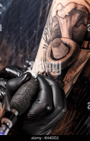 Tattoo Künstler erstellen eine Tätowierung auf dem Arm des Mannes Stockfoto