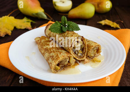 Duftende Süße Pfannkuchen mit karamellisierten Birnen auf einem weissen Teller. Stockfoto