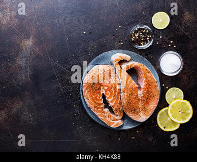 Zwei Steaks von roher Lachs mit Gewürzen und Zitrone schneiden Stockfoto
