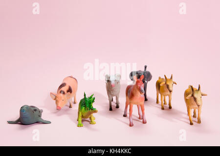 Verschiedene Kunststoff Figur Spielzeug wie Tiere Herde, der auf einer lebhaften Rosa Hintergrund. Minimale still life Fotografie Stockfoto