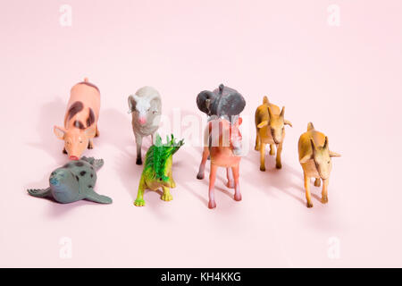 Verschiedene Kunststoff Figur Spielzeug wie Tiere Herde, der auf einer lebhaften Rosa Hintergrund. Minimale still life Fotografie Stockfoto