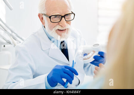 Nahaufnahme der freundliche Arzt Holding falsche Zähne Stockfoto